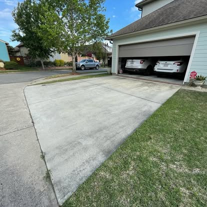Residential concrete driveway mid-clean showing the dirty side next to a freshly pressure-washed strip. Residential concrete driveway mid-clean showing the dirty side next to a freshly pressure-washed strip.